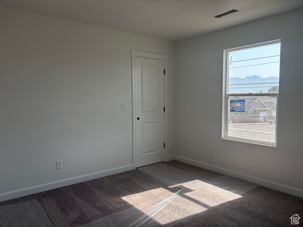 Carpeted empty room with baseboards and a mountain view