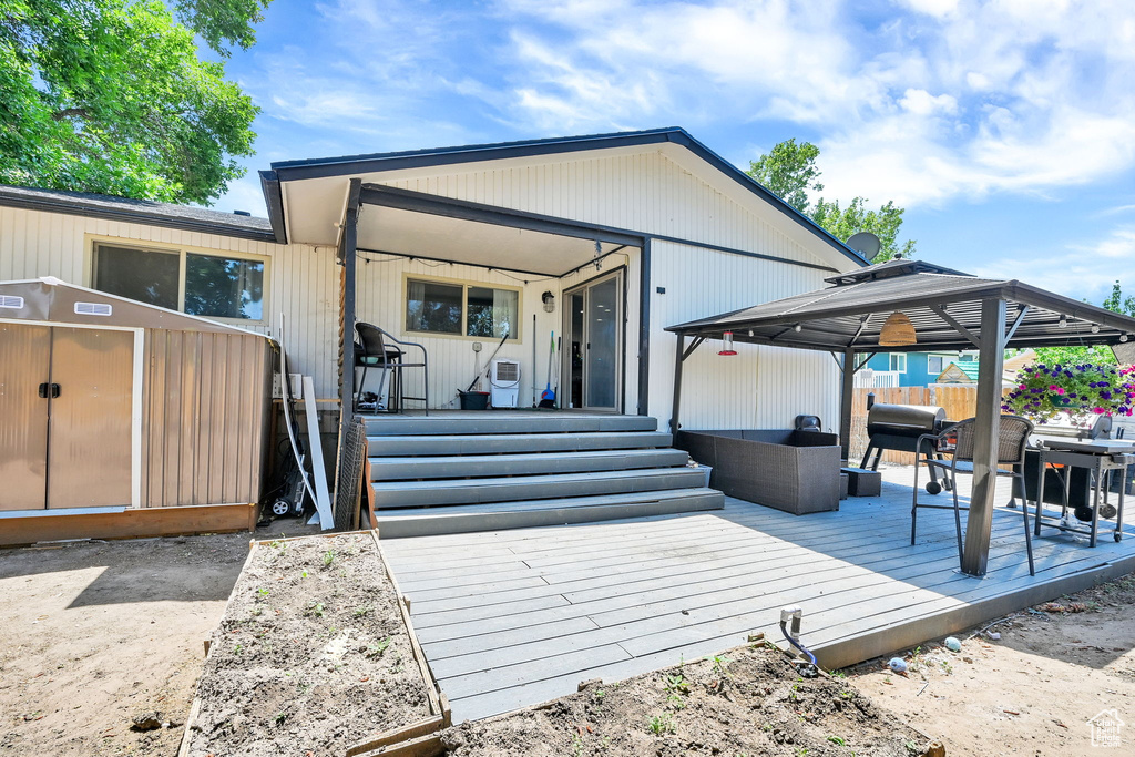 View of front of property featuring a gazebo, a wooden deck, and an outdoor hangout area