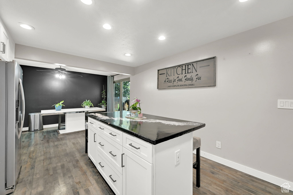 Kitchen featuring stainless steel refrigerator with ice dispenser, dark wood-style floors, a kitchen breakfast bar, a center island, and recessed lighting