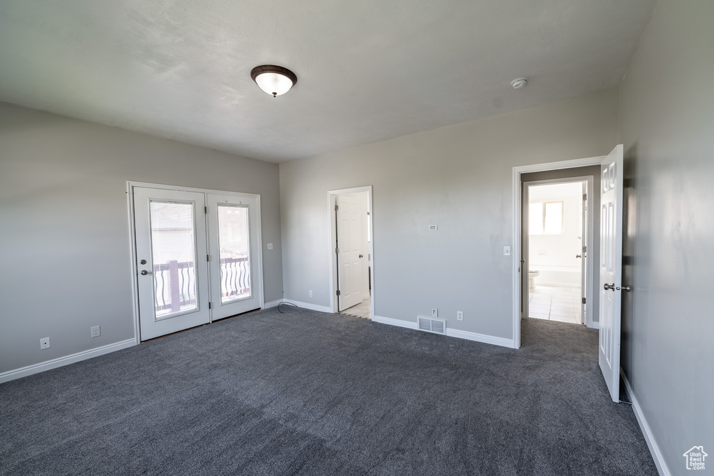 Unfurnished room with healthy amount of natural light, dark colored carpet, and a smoke detector