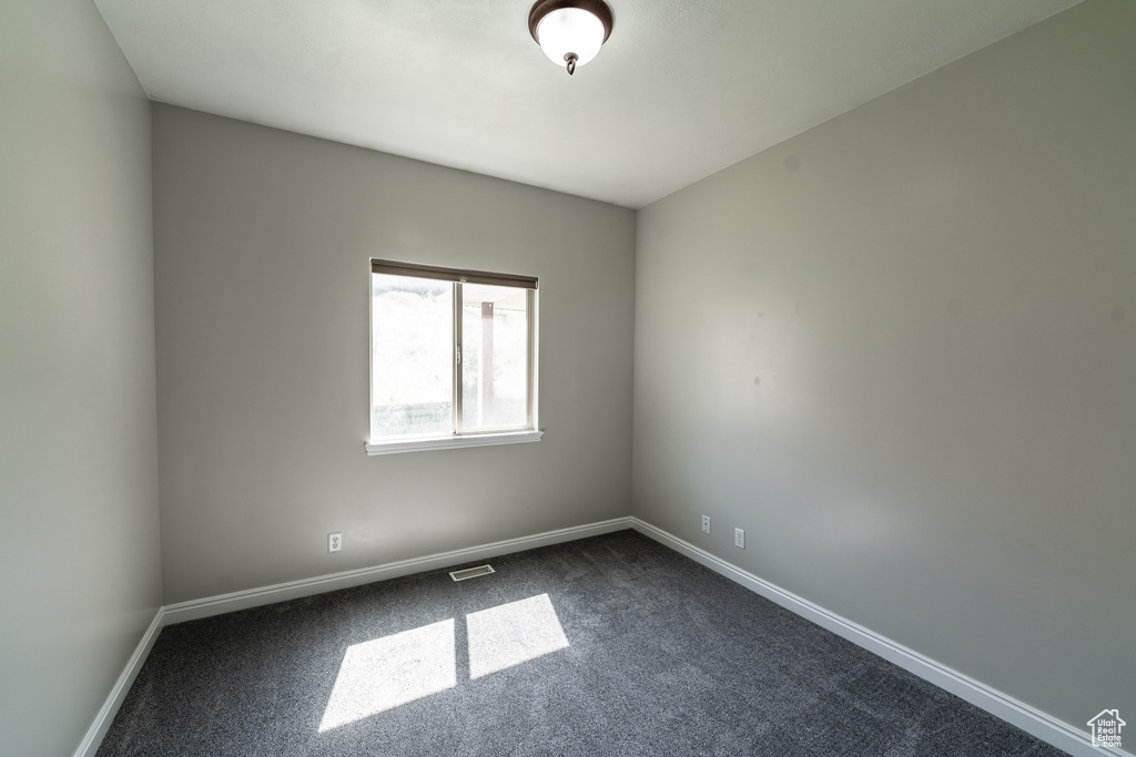 Spare room featuring dark carpet and baseboards