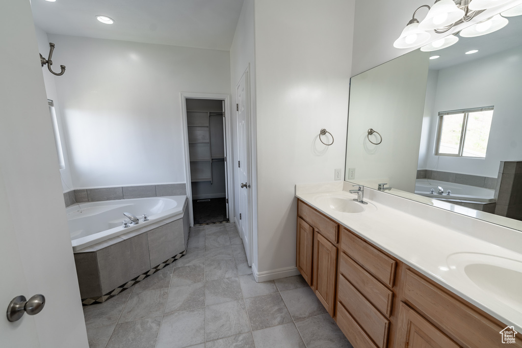 Full bath with a garden tub, double vanity, a walk in closet, and a chandelier