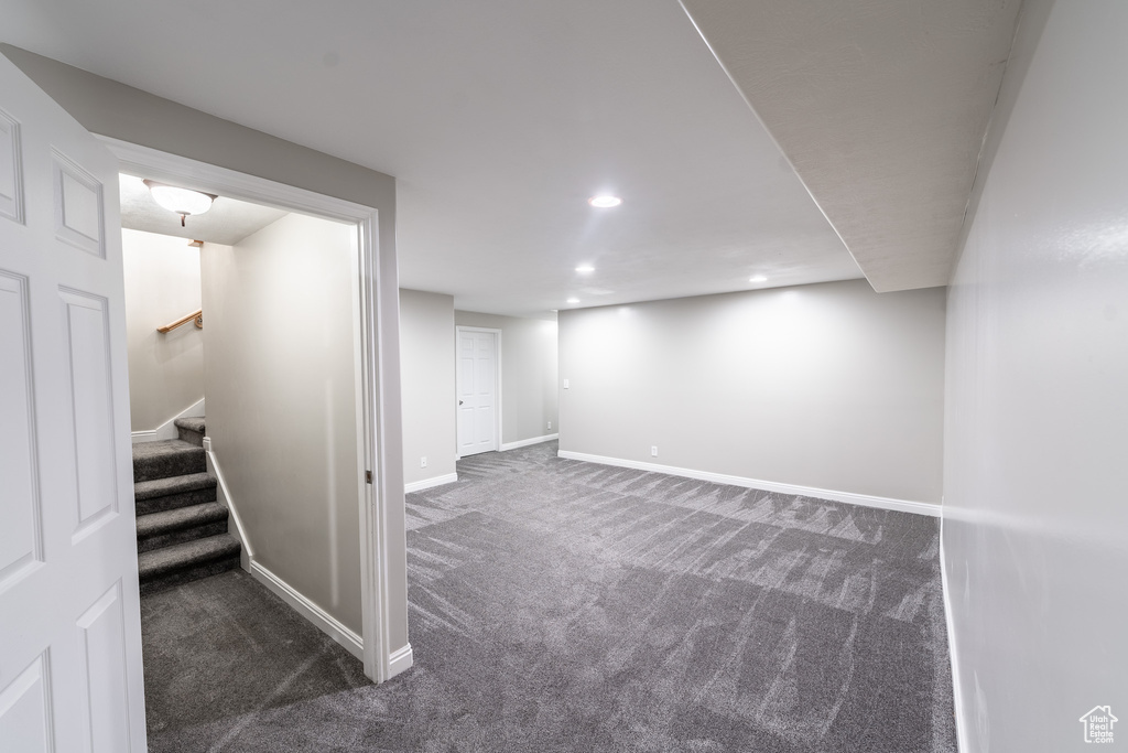 Finished basement with dark carpet, stairway, and recessed lighting