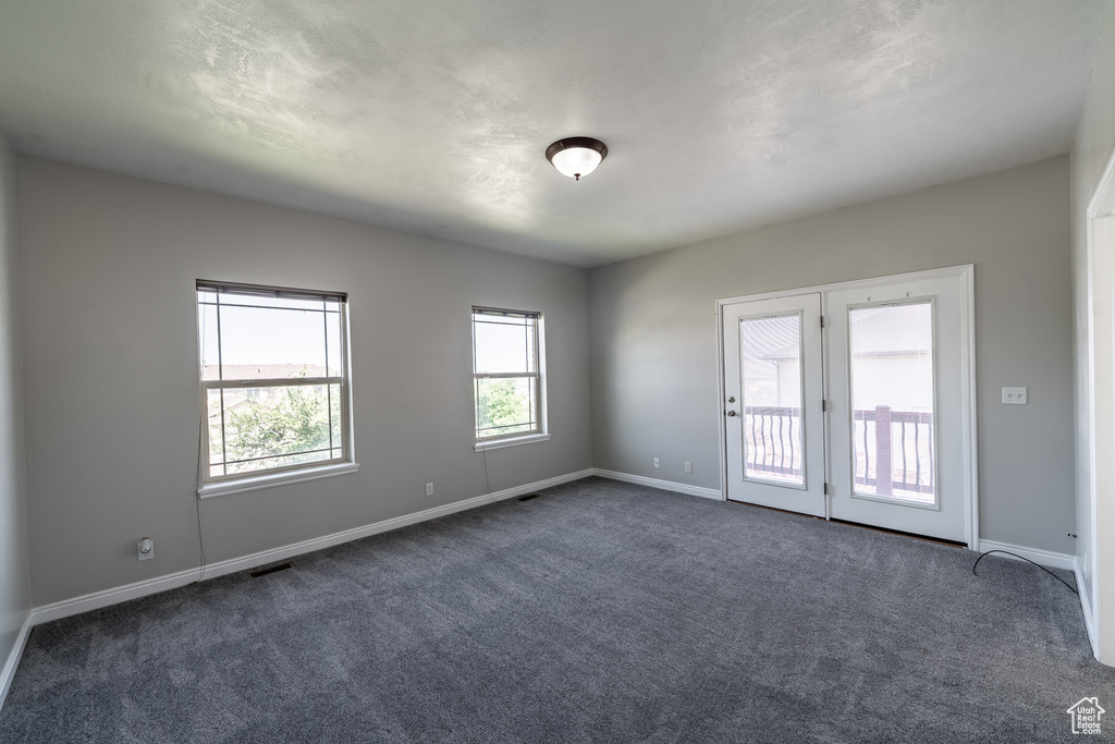 Spare room with dark colored carpet and baseboards