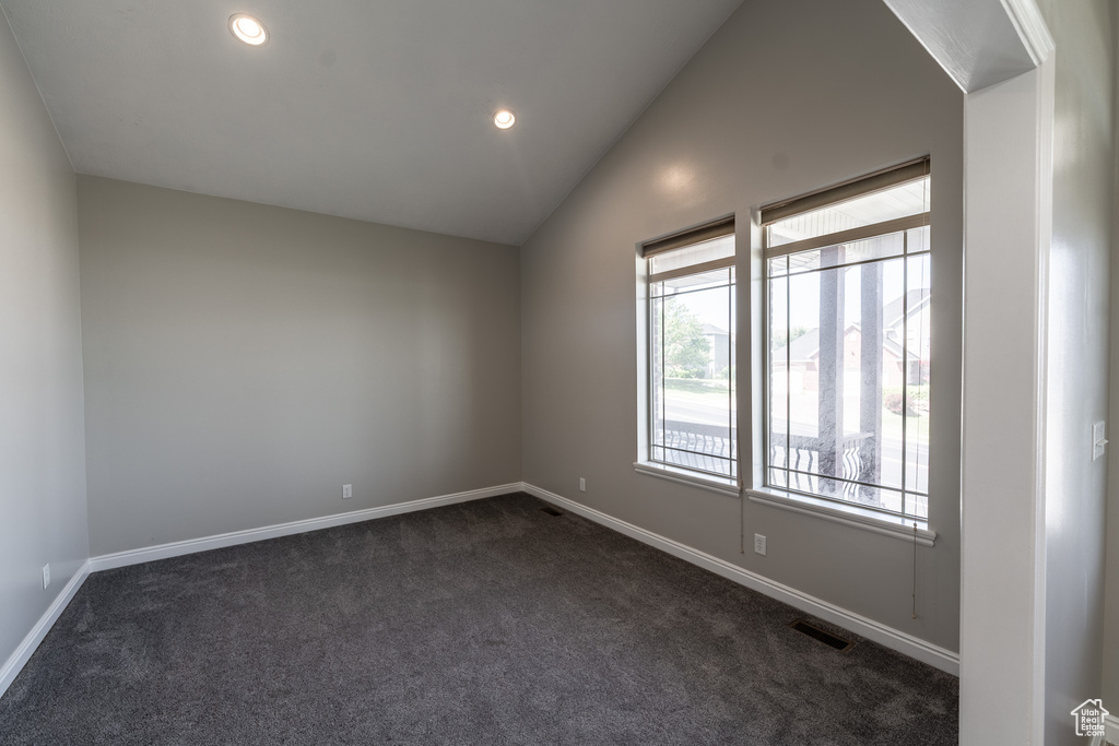 Spare room featuring healthy amount of natural light, dark carpet, vaulted ceiling, and recessed lighting