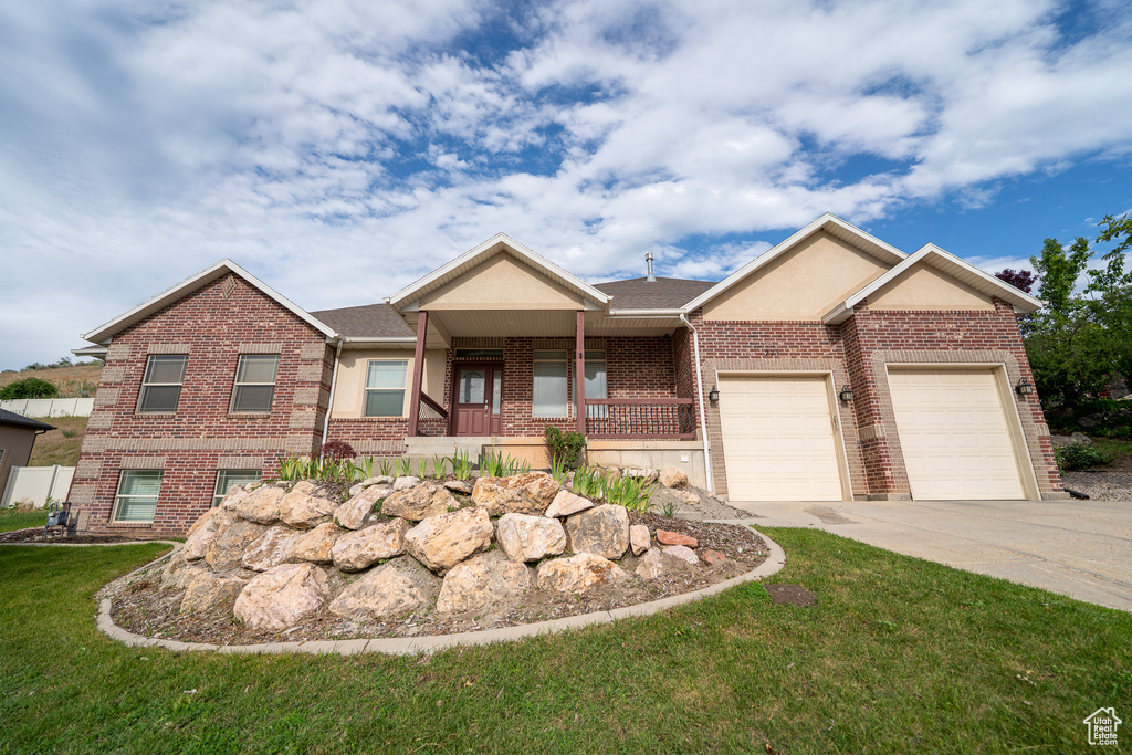 View of front facade featuring brick siding, concrete driveway, a garage, a front lawn, and covered porch