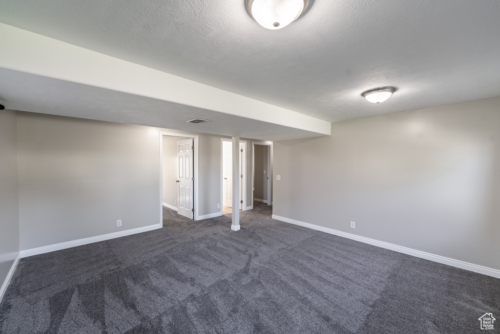 Finished basement featuring baseboards and dark carpet