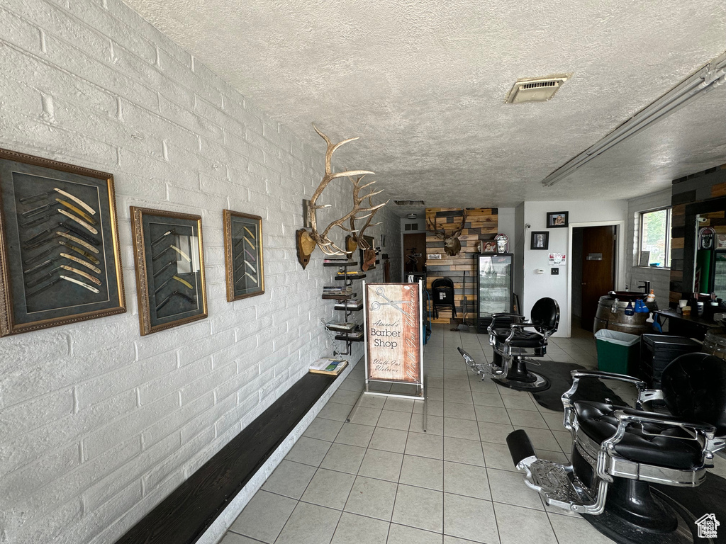 Exercise room featuring tile patterned floors, a textured ceiling, and brick wall