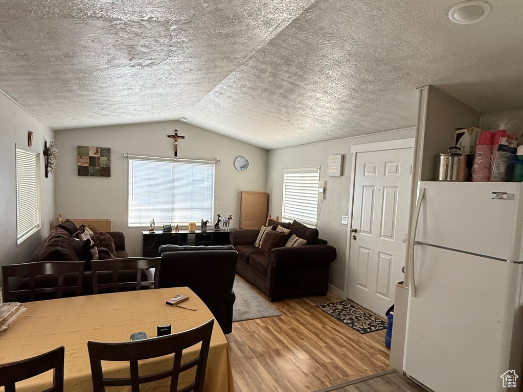 Dining room with wood finished floors, lofted ceiling, and a textured ceiling