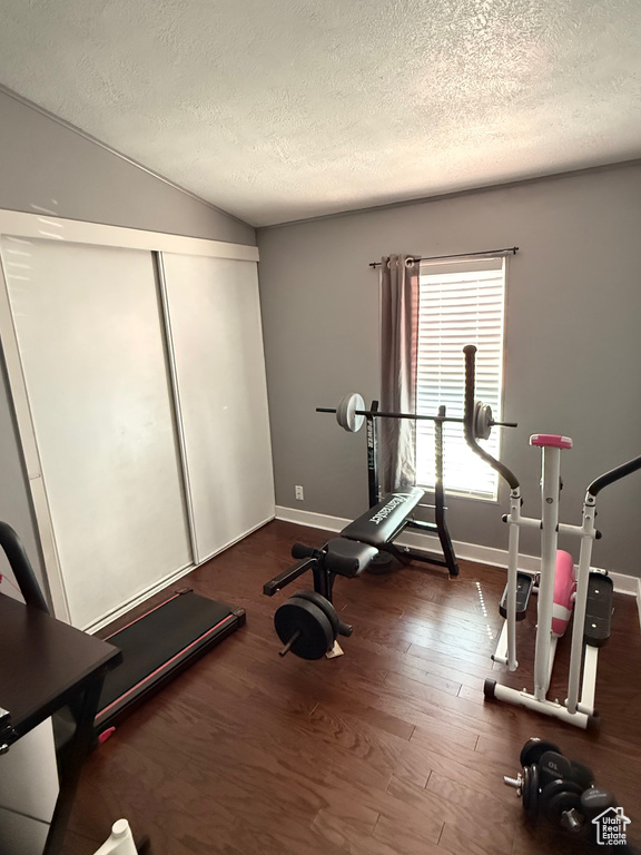 Exercise area with a textured ceiling, wood finished floors, and lofted ceiling