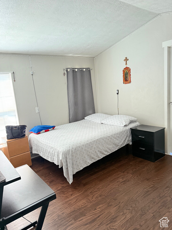 Bedroom with wood finished floors, a textured ceiling, and vaulted ceiling