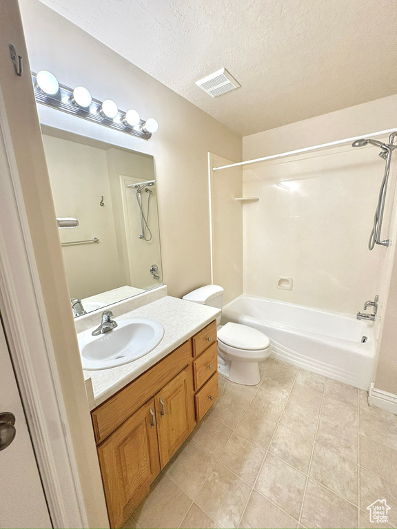 Bathroom featuring washtub / shower combination, vanity, tile patterned floors, and a textured ceiling