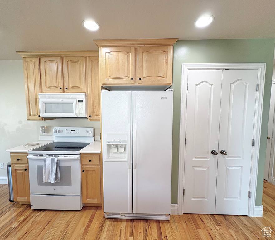 Kitchen featuring white appliances, light brown cabinets, light wood-style flooring, and recessed lighting