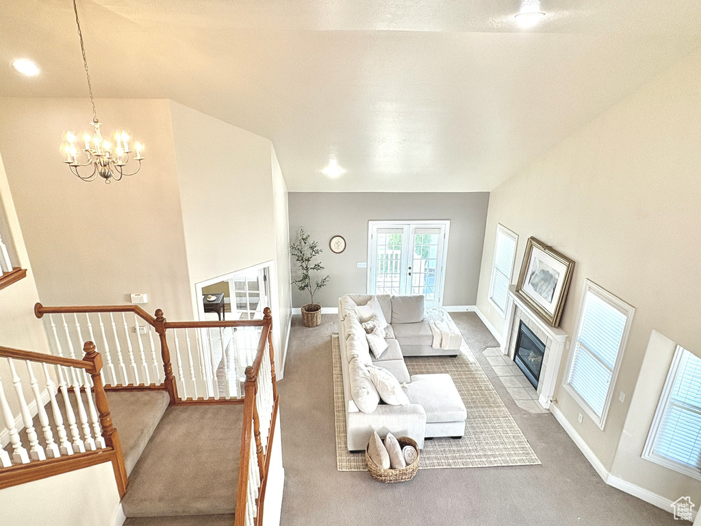 Living area with carpet floors, a chandelier, healthy amount of natural light, and a tiled fireplace