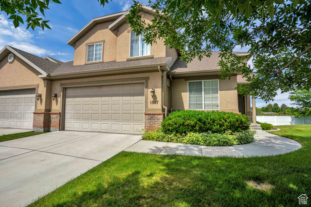View of front of property with stucco siding, a front lawn, driveway, and an attached garage