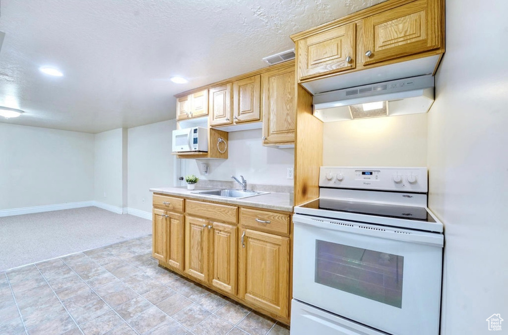 Kitchen featuring white appliances, under cabinet range hood, light countertops, light carpet, and recessed lighting
