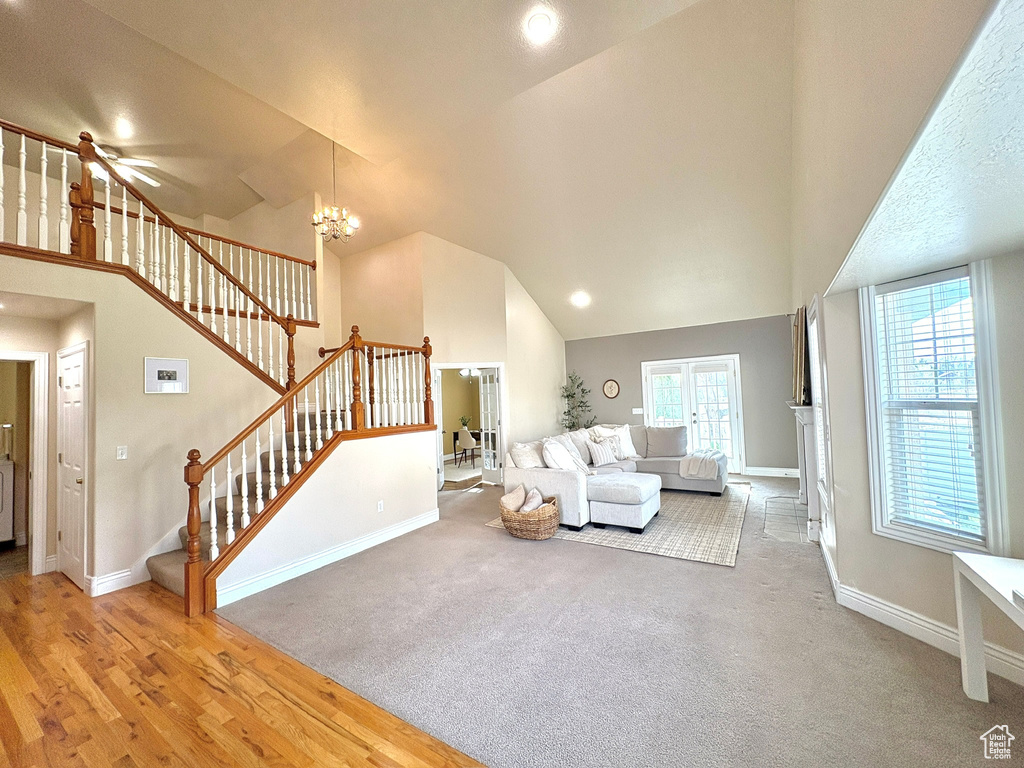 Carpeted living room with stairway, high vaulted ceiling, and a chandelier