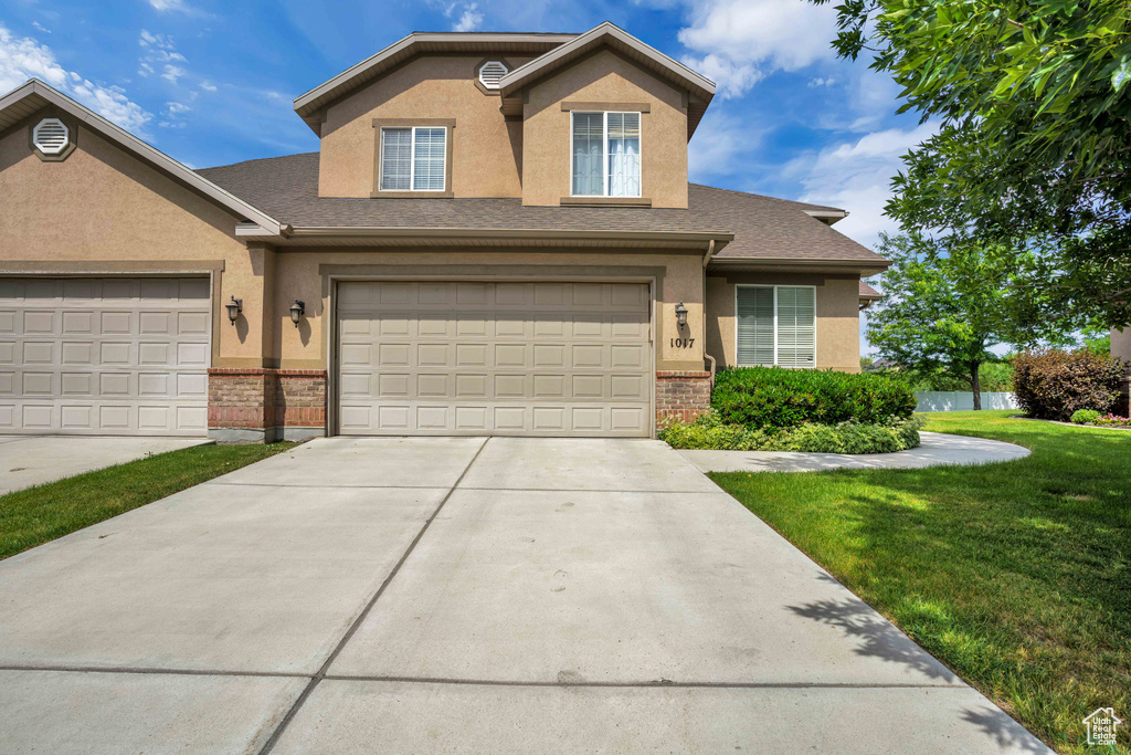 Traditional-style home featuring brick siding, stucco siding, and a front yard