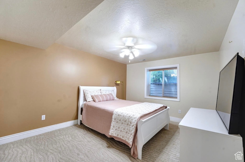 Bedroom featuring a textured ceiling, light carpet, and a ceiling fan