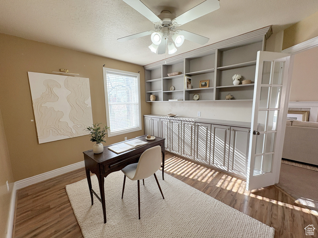 Office with wood finished floors, a ceiling fan, and french doors