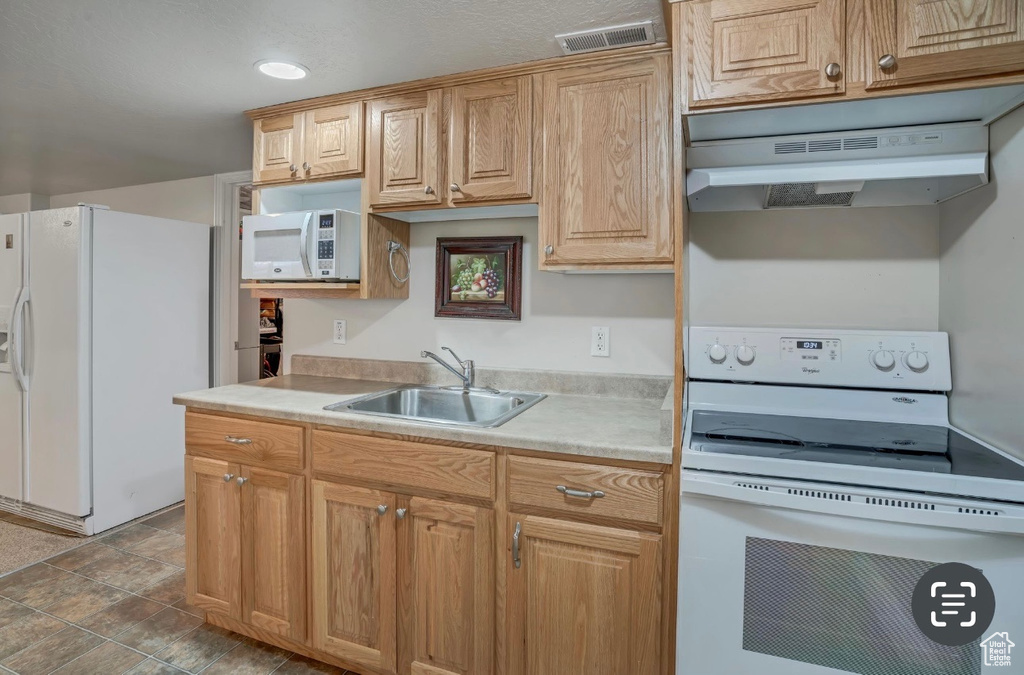 Kitchen featuring white appliances, under cabinet range hood, and light countertops