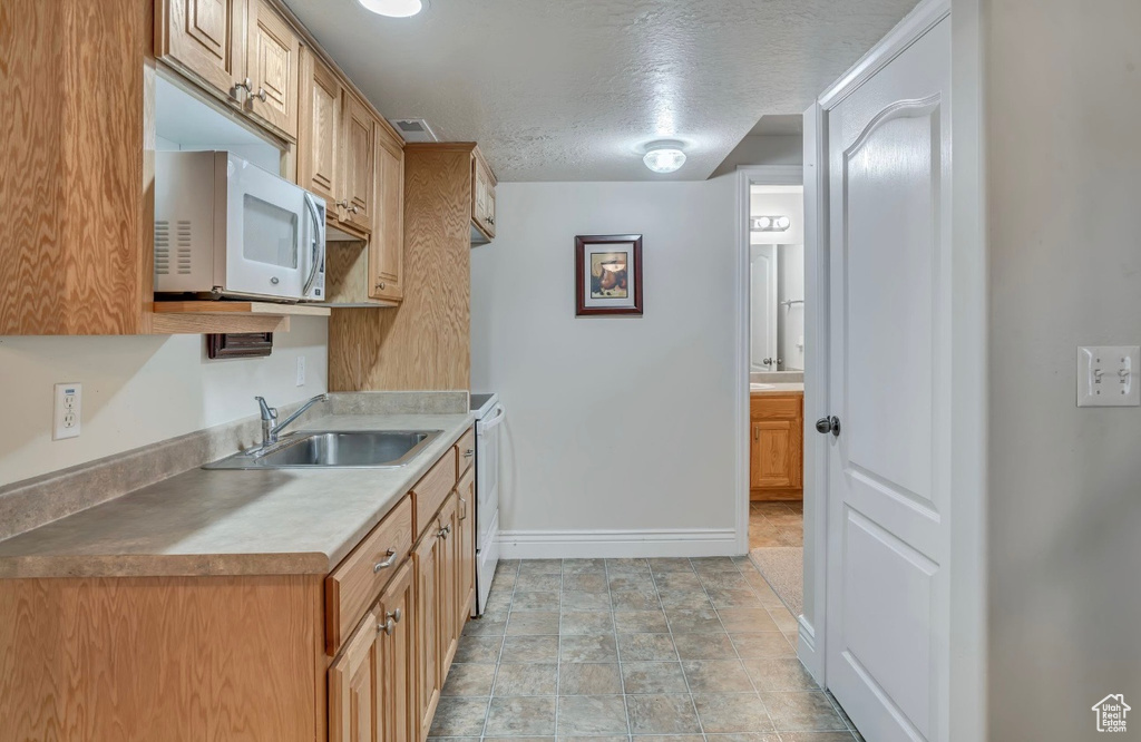 Kitchen featuring white microwave, a textured ceiling, and light countertops