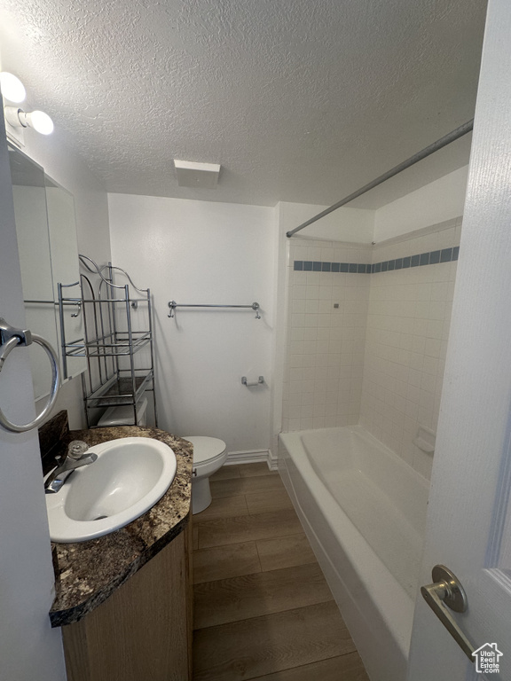Full bathroom with vanity, a textured ceiling, wood finished floors, and washtub / shower combination