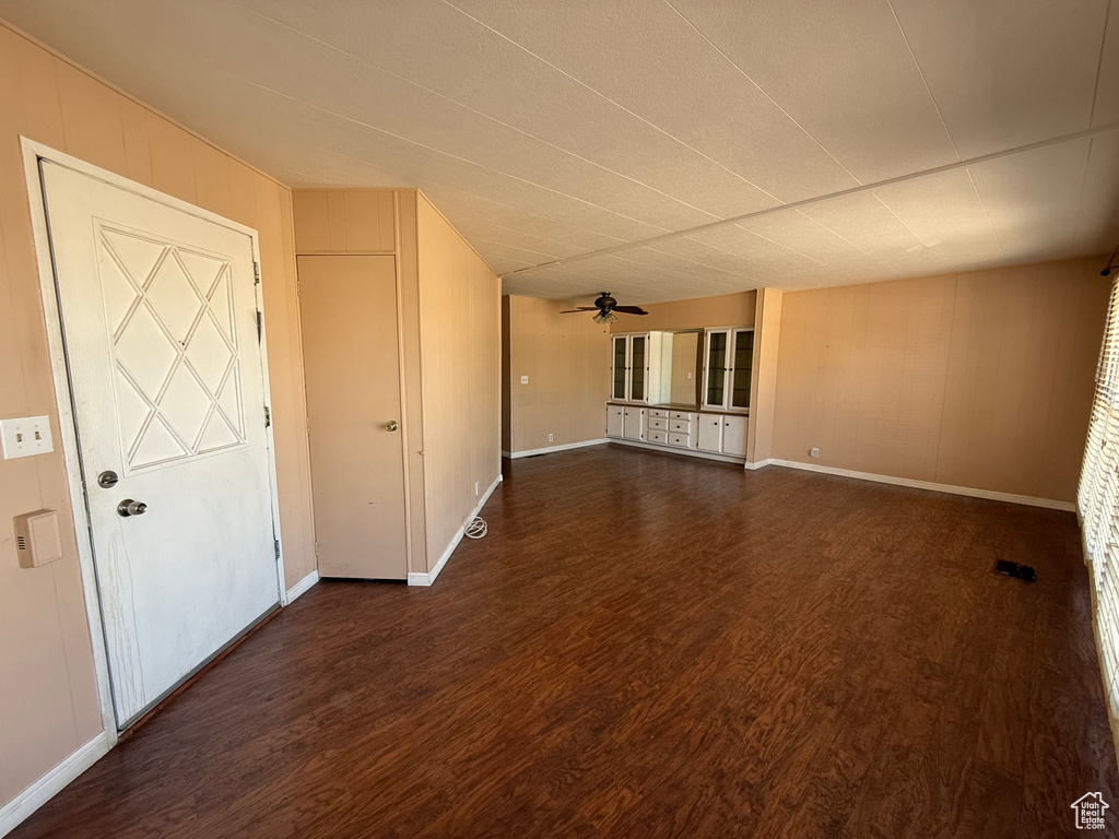 Spare room with dark wood-style flooring and baseboards