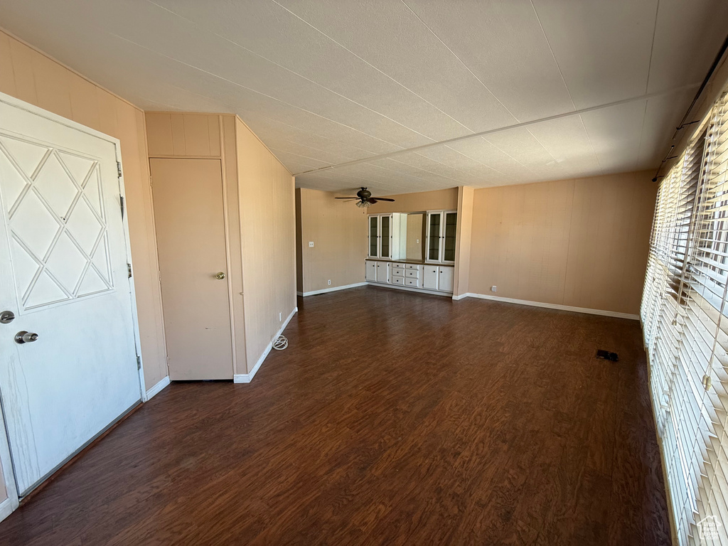 Unfurnished room with dark wood-style flooring and ceiling fan