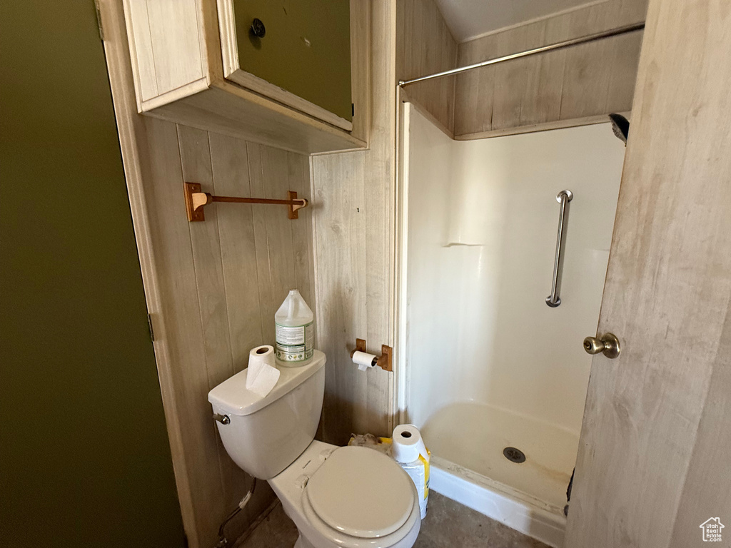 Bathroom featuring a stall shower and wood walls