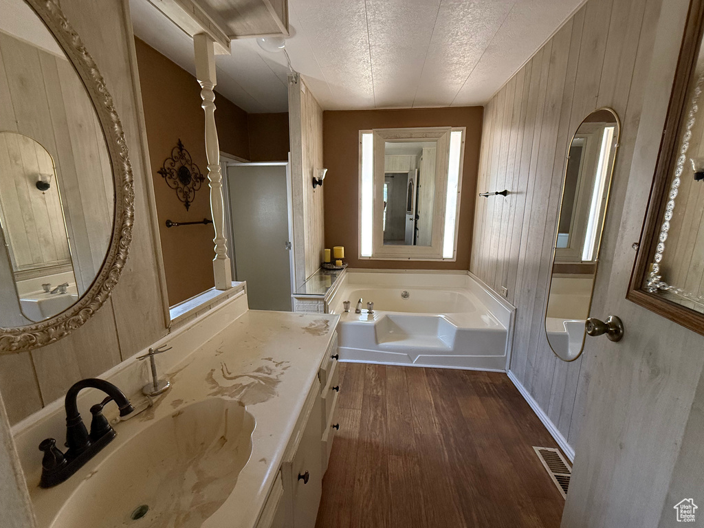 Full bathroom with wood finished floors, a garden tub, vanity, a shower stall, and wood walls