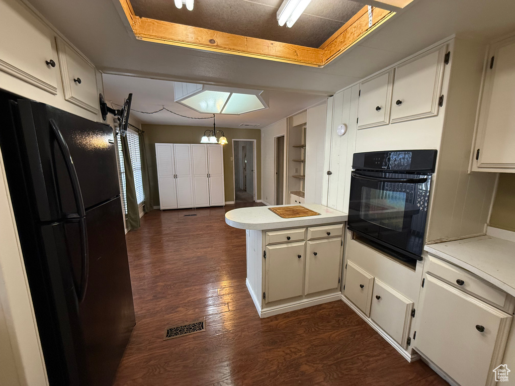 Kitchen featuring black appliances, a peninsula, dark wood-style floors, and light countertops