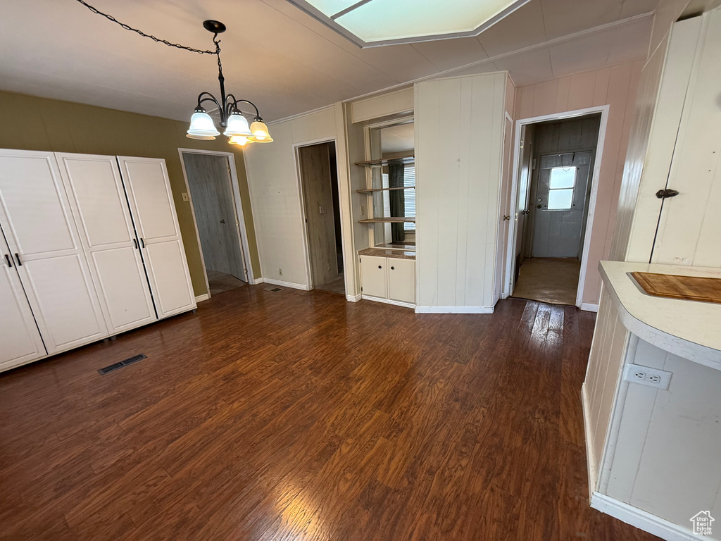 Unfurnished dining area featuring dark wood-type flooring and a chandelier