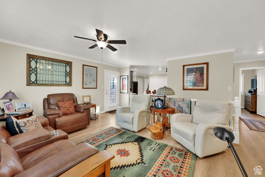 Living room featuring ceiling fan, ornamental molding, light wood-type flooring, baseboards, and recessed lighting