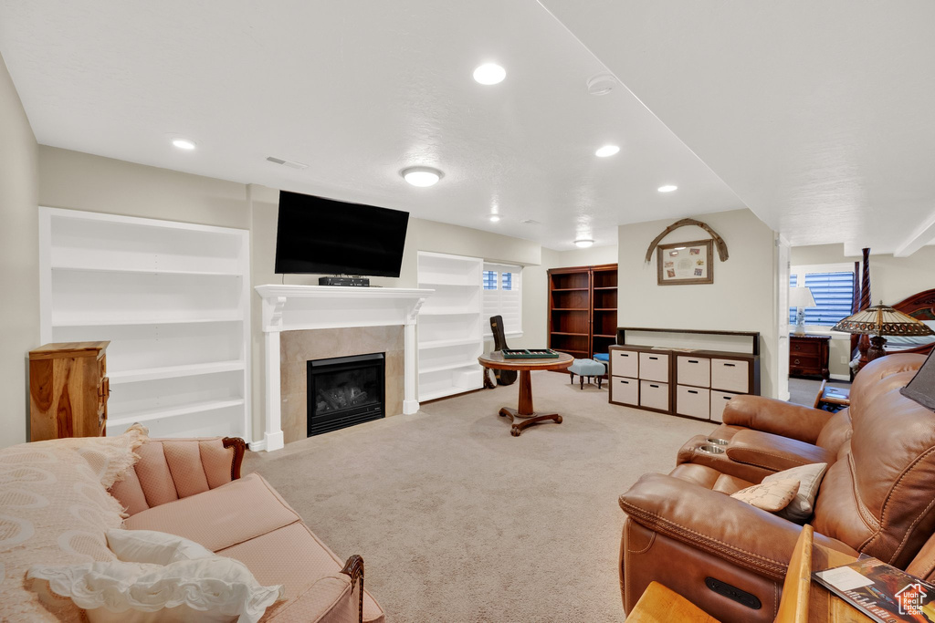 Carpeted living area featuring recessed lighting, a tiled fireplace, and built in features