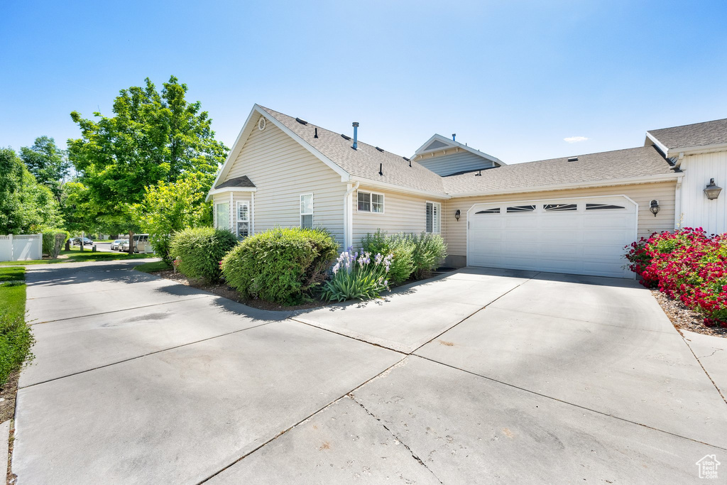 View of front of home with driveway, a garage, and roof with shingles