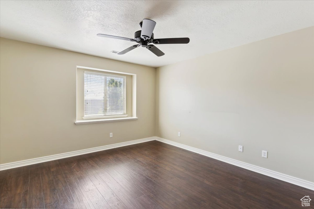 Spare room featuring dark wood-style flooring, ceiling fan, and a textured ceiling