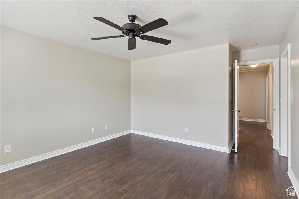 Unfurnished room featuring ceiling fan, dark wood finished floors, and a textured ceiling