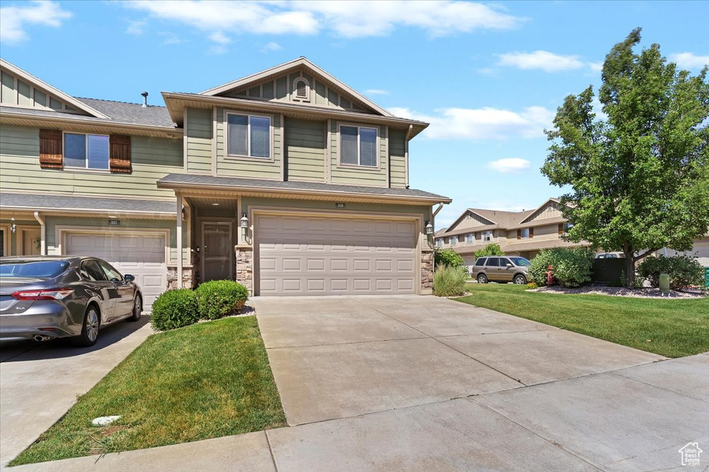 View of front of house with an attached garage, concrete driveway, a front lawn, and board and batten siding