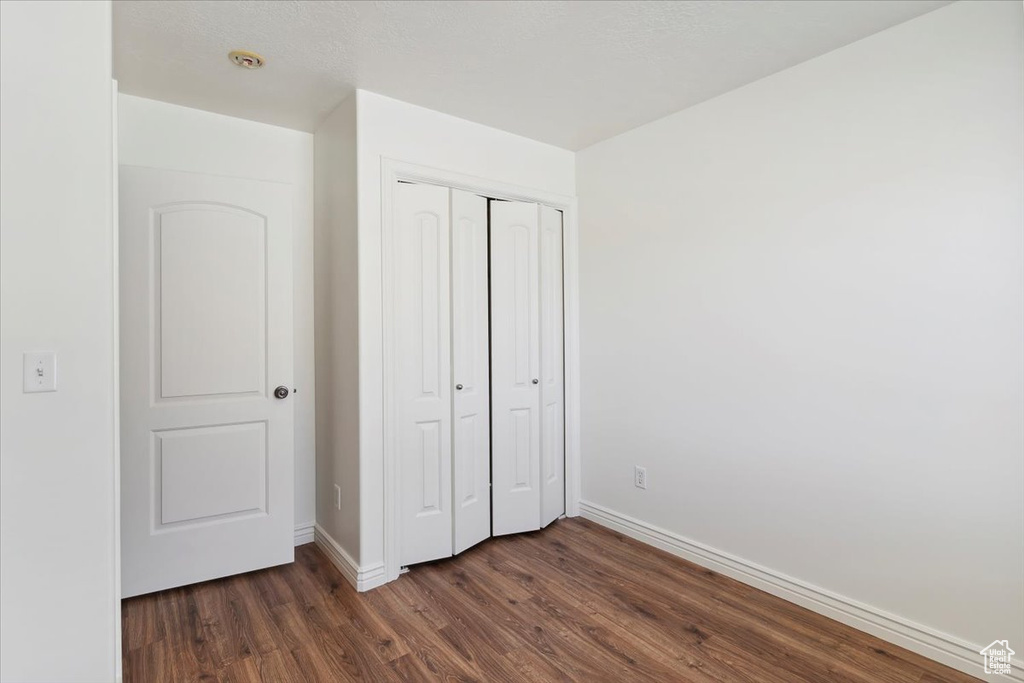 Unfurnished bedroom featuring dark wood-style floors and a closet