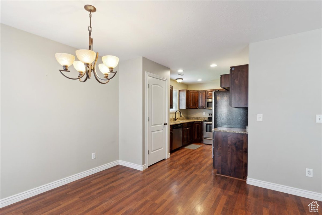 Kitchen with stainless steel appliances, a chandelier, dark wood finished floors, light countertops, and dark brown cabinets