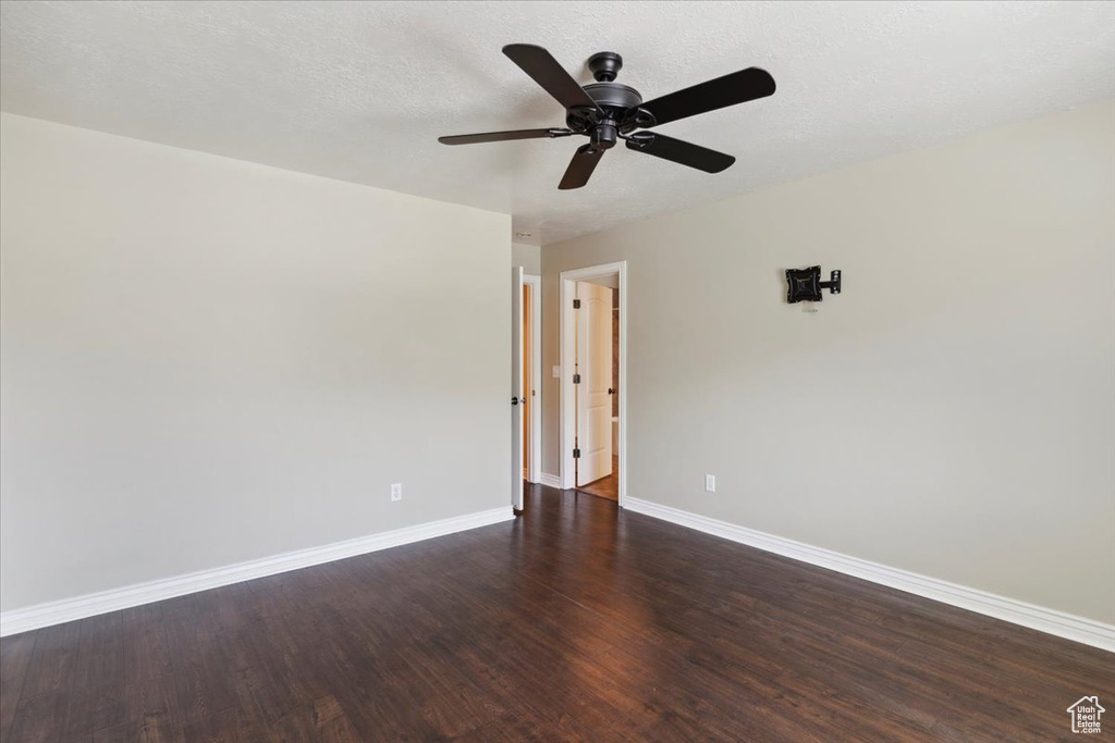 Unfurnished room featuring ceiling fan and dark wood-type flooring