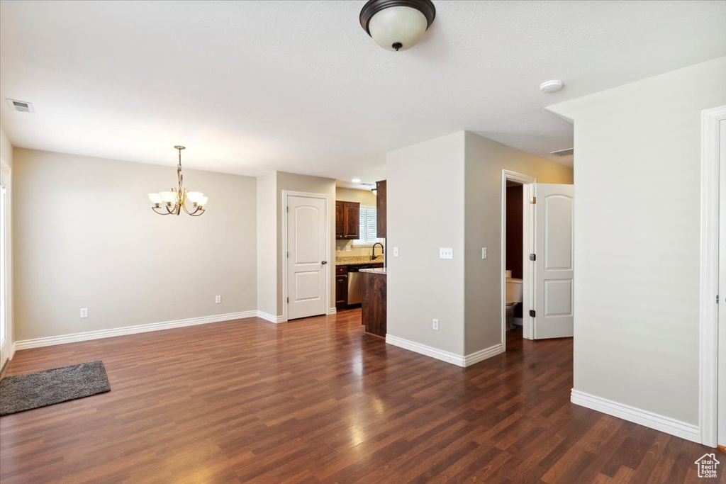Unfurnished living room with a chandelier and dark wood finished floors
