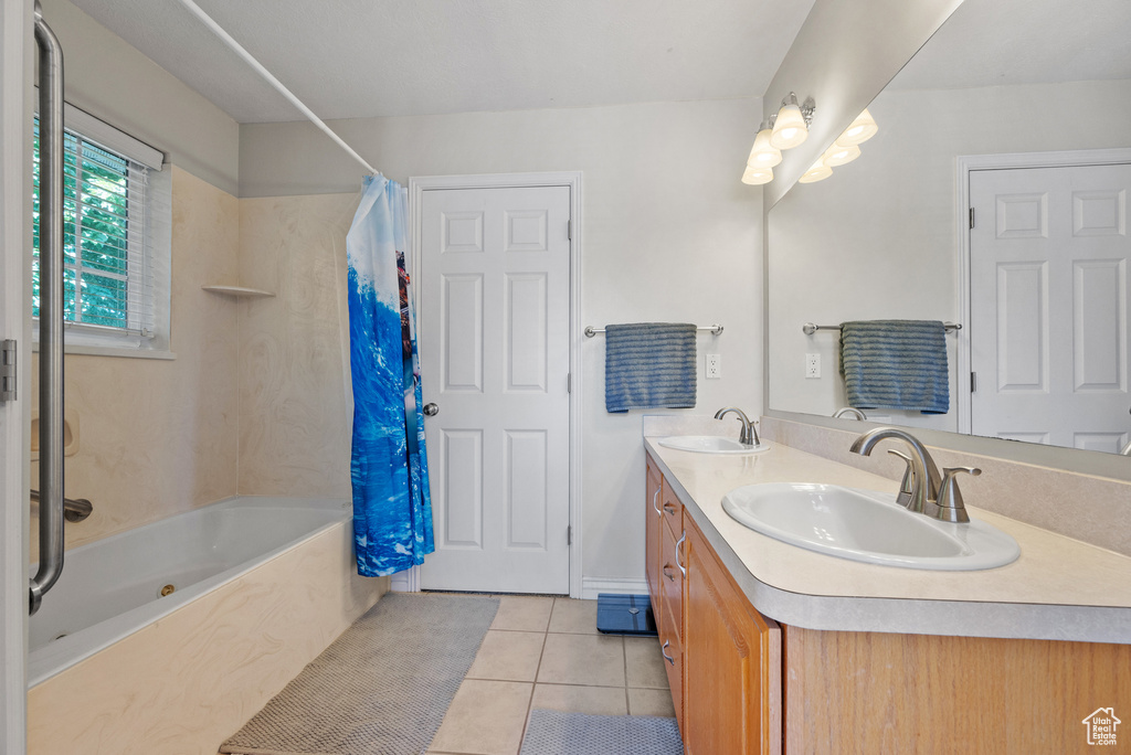 Bathroom with tile patterned flooring, shower / bath combination with curtain, and double vanity