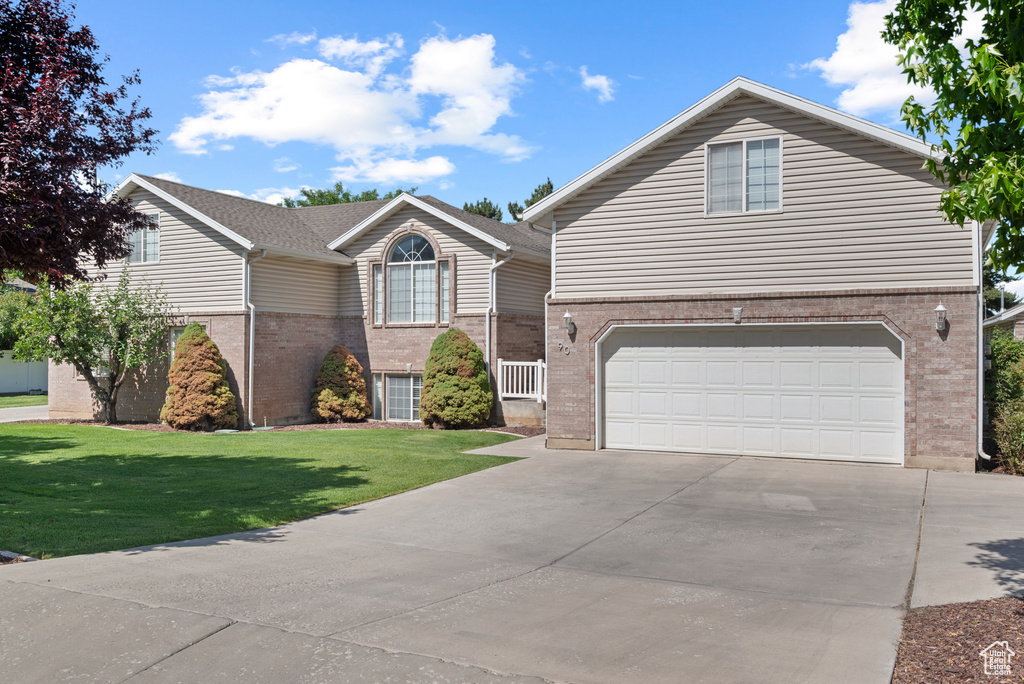 Traditional-style house with brick siding, driveway, an attached garage, and a front lawn
