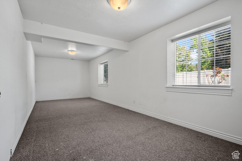Carpeted spare room featuring baseboards