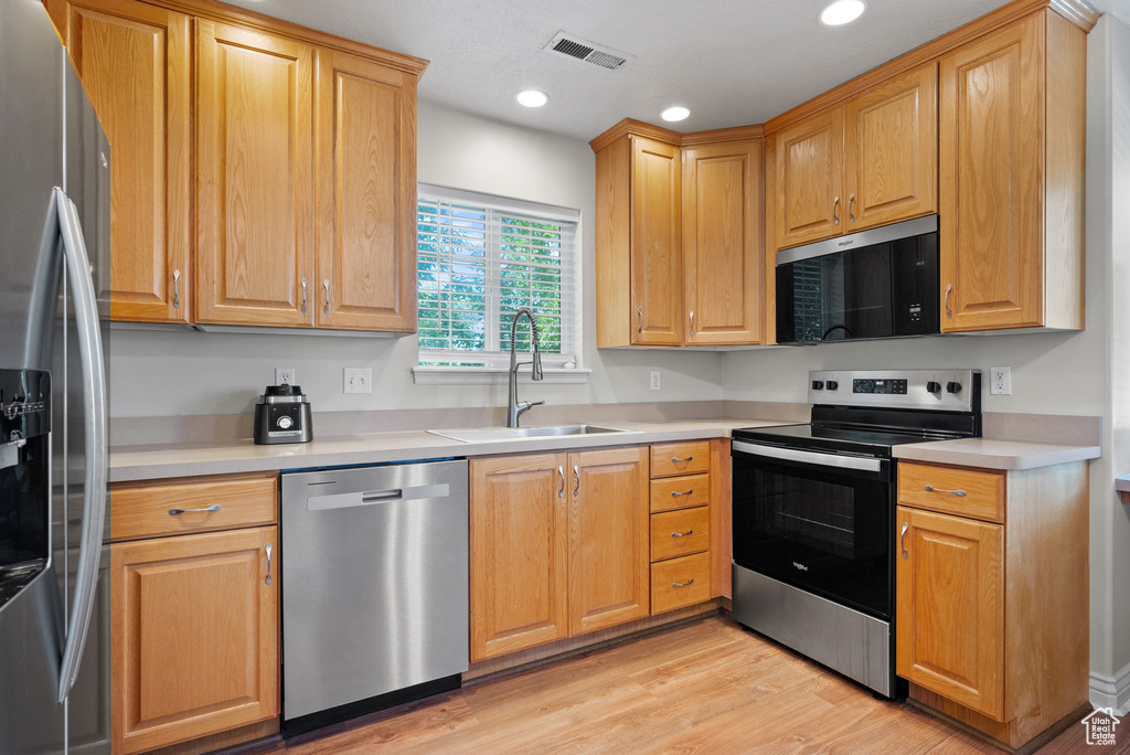 Kitchen with appliances with stainless steel finishes, light wood-style floors, light countertops, and recessed lighting