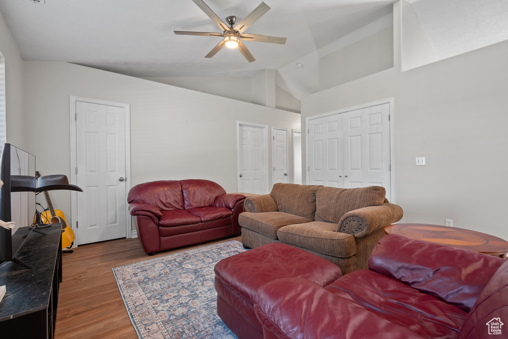 Living room with vaulted ceiling, ceiling fan, and wood finished floors