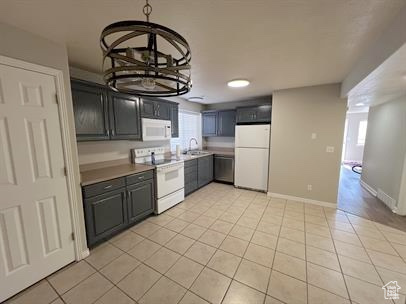 Kitchen with white appliances, light tile patterned floors, and healthy amount of natural light
