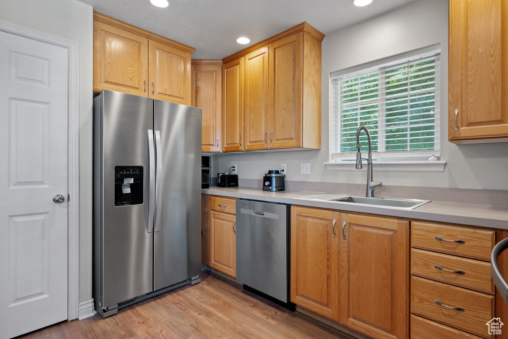 Kitchen with stainless steel appliances, light wood-style flooring, light countertops, and recessed lighting